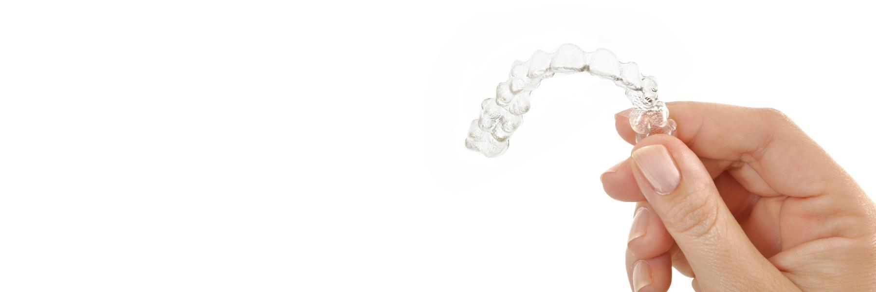 Hand holding Invisalign clear aligners in Aston, PA